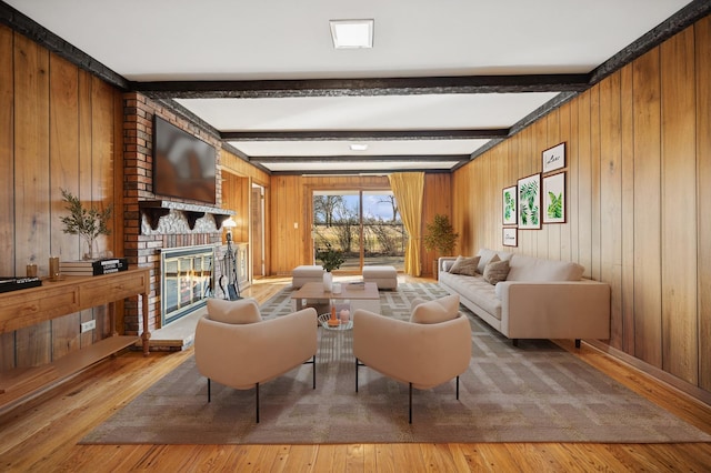 sitting room featuring hardwood / wood-style floors, beamed ceiling, wooden walls, and a fireplace