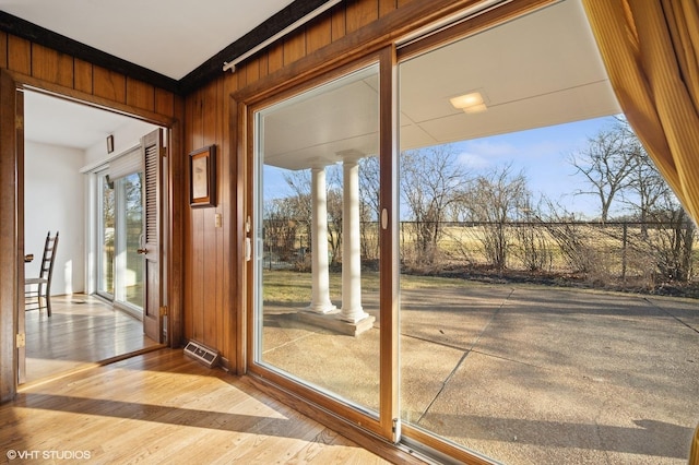 doorway with wooden walls, wood finished floors, and visible vents