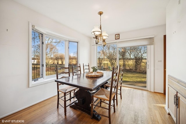 dining space featuring an inviting chandelier, baseboards, and light wood-style floors