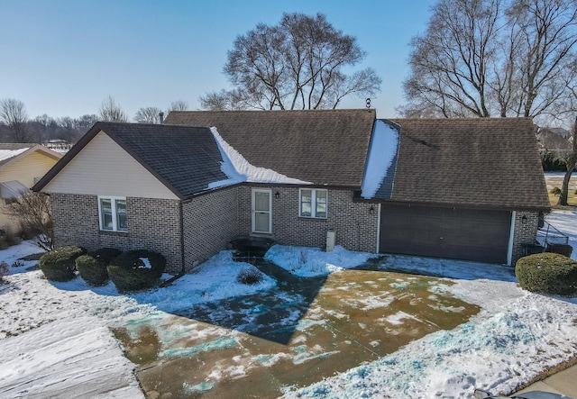 view of front facade with an attached garage, driveway, roof with shingles, and brick siding