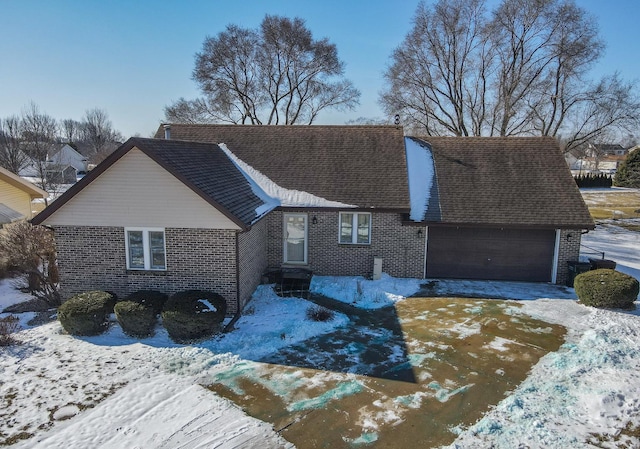 view of front of house with a garage, driveway, roof with shingles, and brick siding