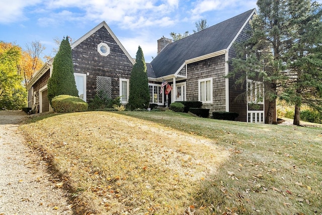 view of front of home featuring a garage, a chimney, and a front lawn