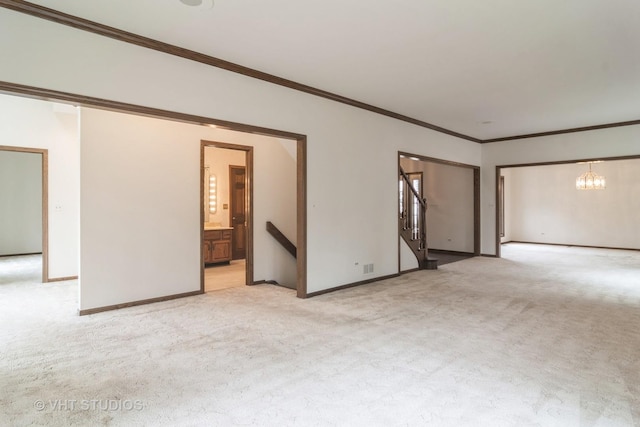 unfurnished room featuring a notable chandelier, light colored carpet, visible vents, baseboards, and ornamental molding