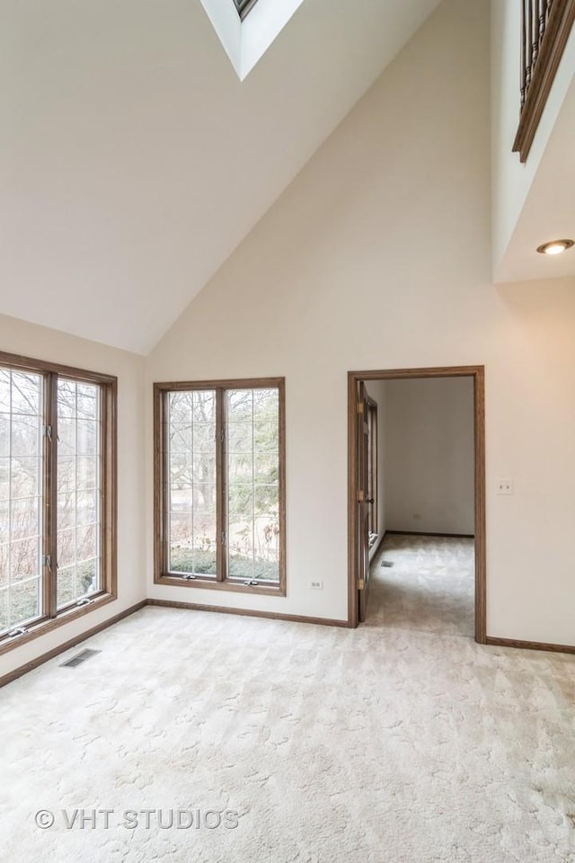 empty room with light carpet, a skylight, baseboards, and visible vents