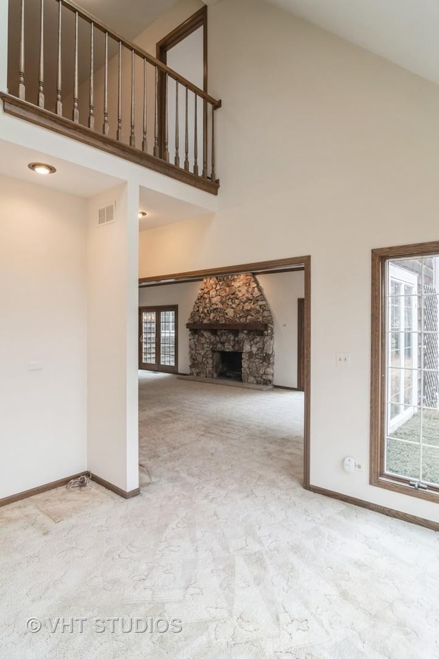 unfurnished living room featuring high vaulted ceiling, carpet floors, a fireplace, visible vents, and baseboards