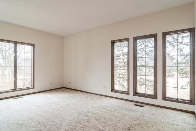 carpeted spare room featuring visible vents and baseboards