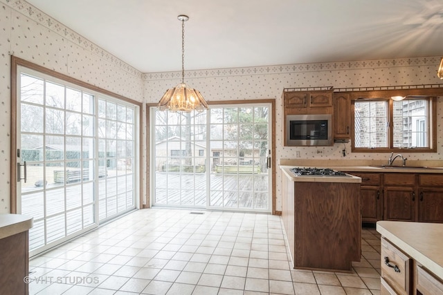 kitchen with light countertops, stainless steel microwave, a sink, and wallpapered walls