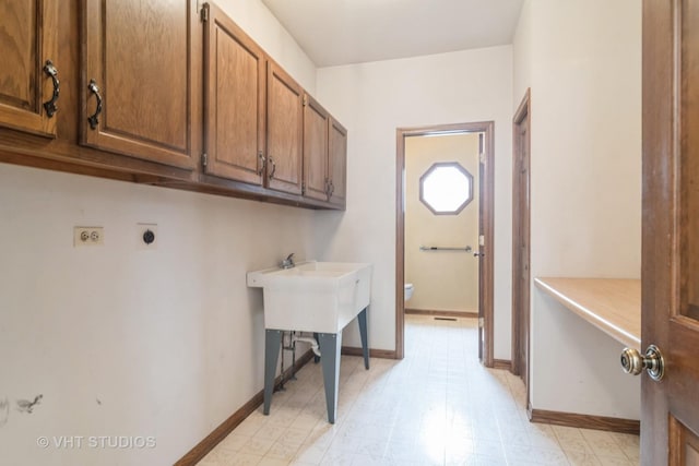 laundry room featuring cabinet space, baseboards, light floors, and electric dryer hookup