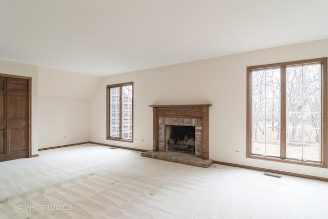 unfurnished living room with visible vents, a fireplace, light carpet, and baseboards