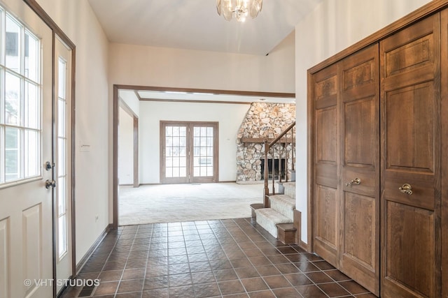 foyer entrance featuring a notable chandelier, baseboards, stairs, french doors, and dark colored carpet