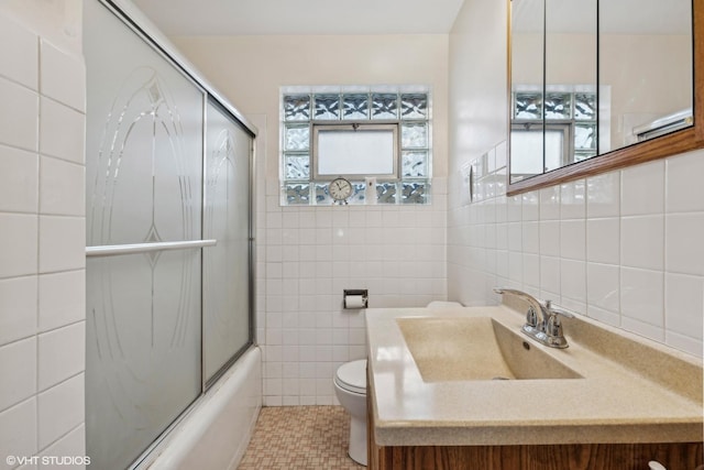 full bathroom with toilet, combined bath / shower with glass door, tile walls, and vanity