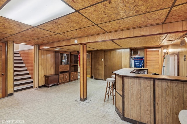 finished basement with stairs, light floors, and wood walls