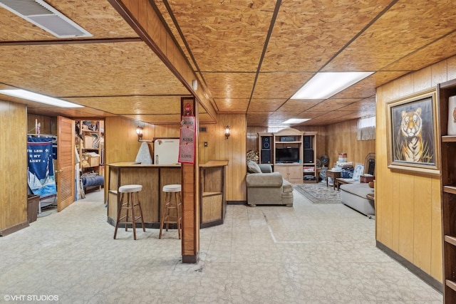 living area featuring light floors, a dry bar, wood walls, and visible vents