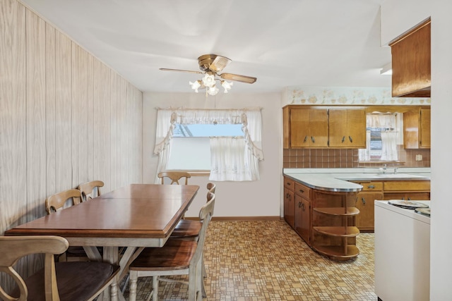 kitchen featuring ceiling fan, light countertops, range, tasteful backsplash, and brown cabinetry