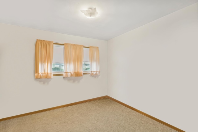 empty room featuring carpet and baseboards