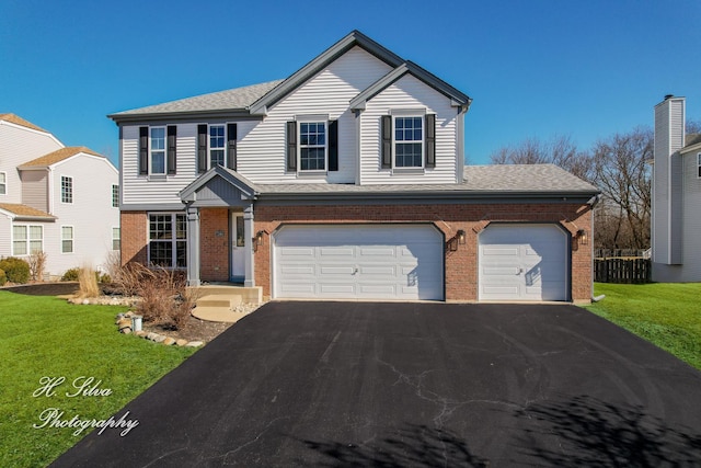 traditional-style house with aphalt driveway, brick siding, and a front lawn