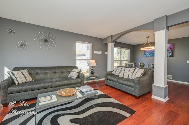 living area featuring decorative columns, wood finished floors, and arched walkways