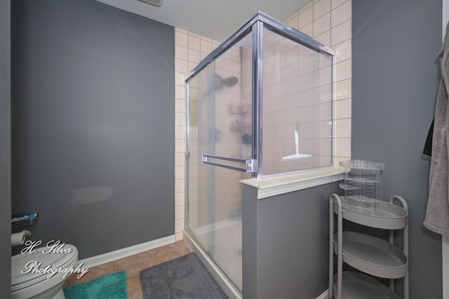 full bath with tile patterned floors, a shower stall, and toilet