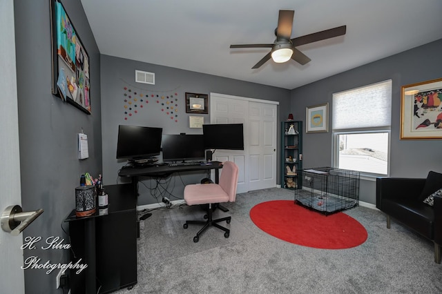 carpeted office space featuring visible vents, baseboards, and ceiling fan