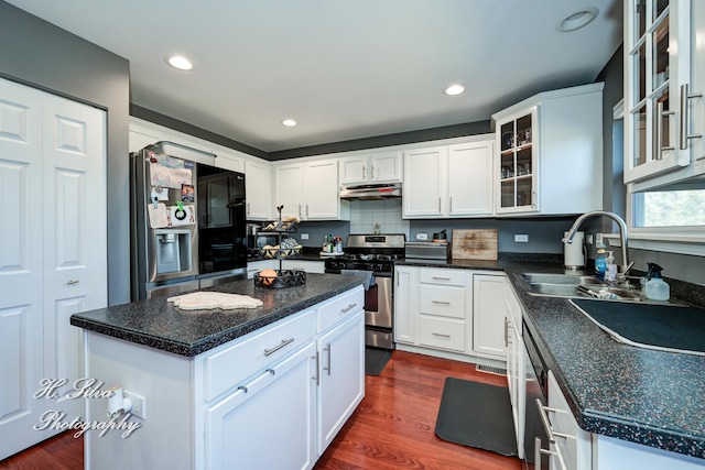 kitchen with under cabinet range hood, appliances with stainless steel finishes, dark wood-style floors, white cabinets, and a sink