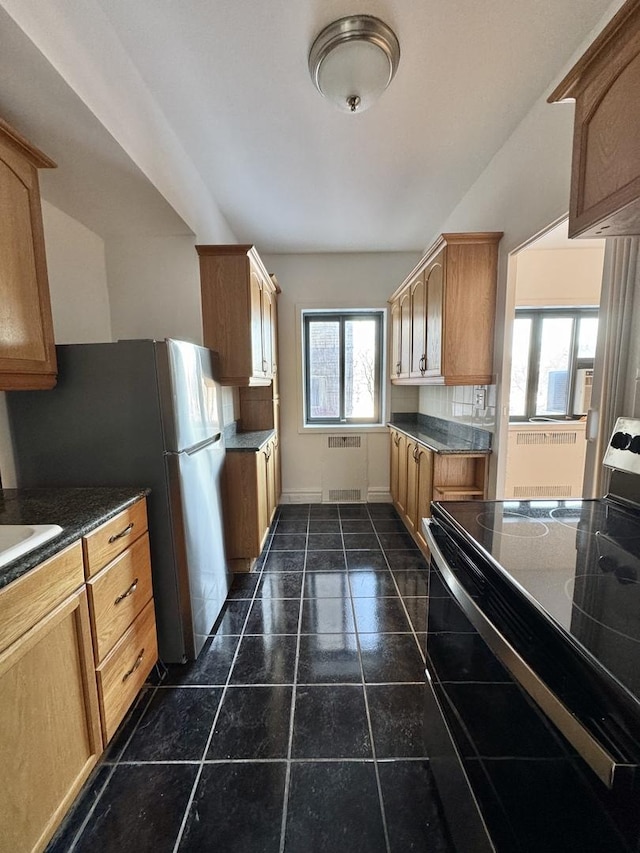 kitchen featuring tasteful backsplash, electric stove, dark tile patterned flooring, dark countertops, and freestanding refrigerator