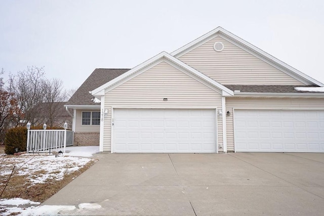 view of front of home with a garage, concrete driveway, and roof with shingles