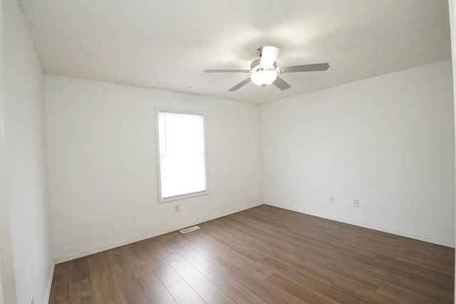 empty room featuring dark wood-type flooring, visible vents, and a ceiling fan