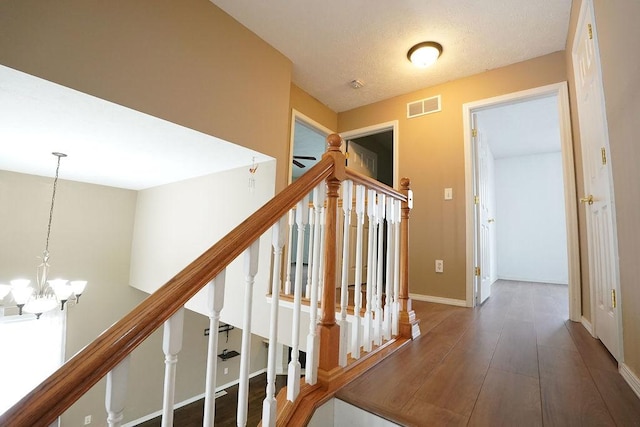 hall with baseboards, visible vents, dark wood finished floors, stairway, and a notable chandelier