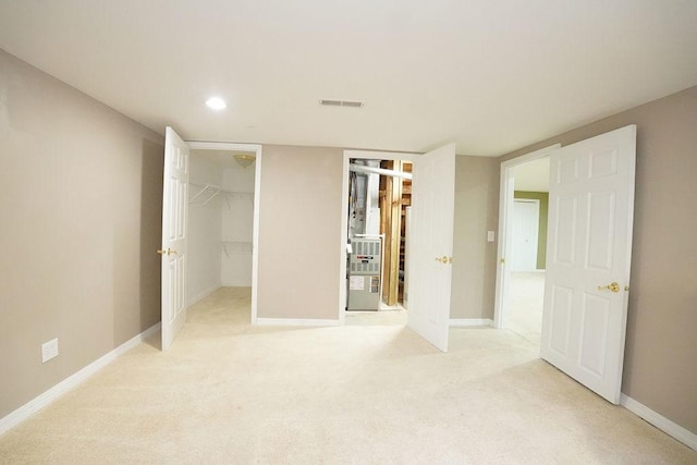 unfurnished bedroom with recessed lighting, light colored carpet, visible vents, baseboards, and a spacious closet