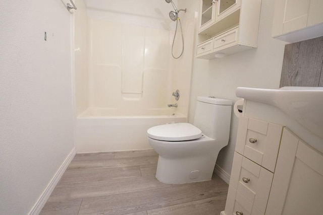 bathroom featuring shower / tub combination, toilet, wood finished floors, vanity, and baseboards