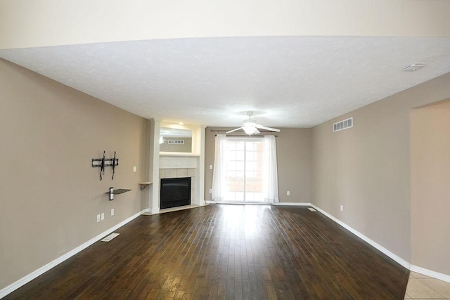 unfurnished living room featuring visible vents, baseboards, wood finished floors, and a tile fireplace