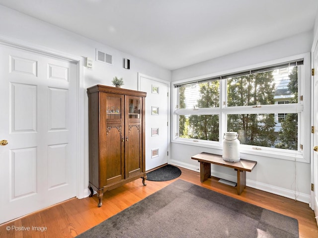 living area with visible vents, baseboards, and wood finished floors