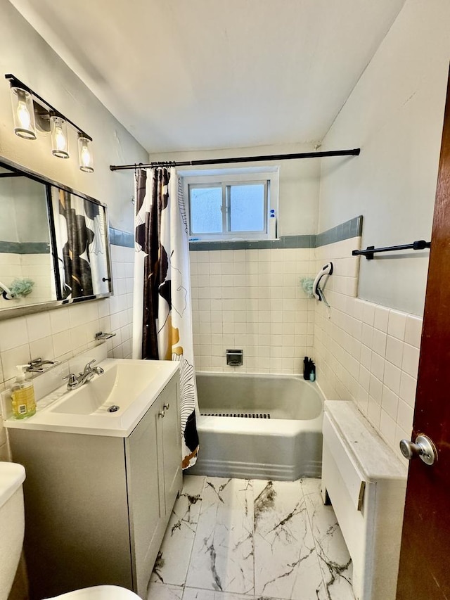 bathroom featuring toilet, marble finish floor, shower / bath combination with curtain, and tile walls