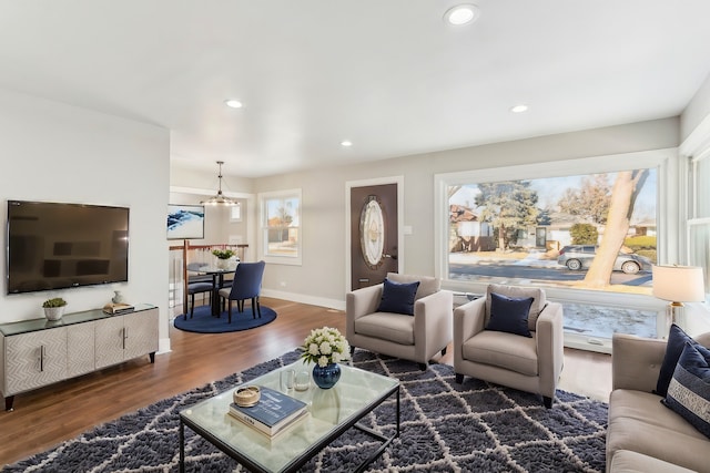 living area with dark wood-type flooring, recessed lighting, a chandelier, and baseboards