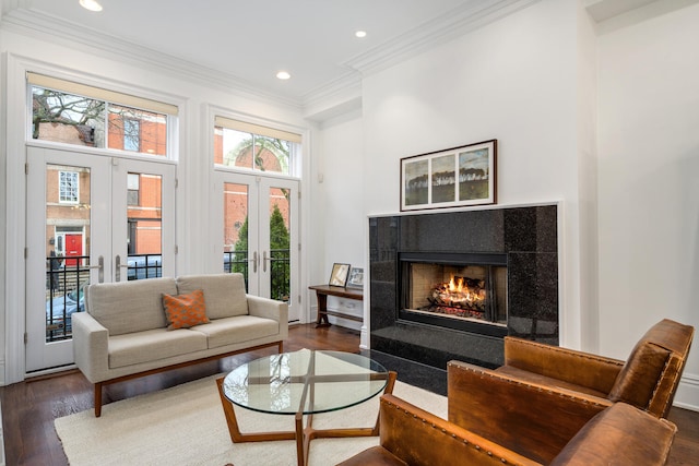 sitting room with recessed lighting, dark wood-style flooring, a lit fireplace, french doors, and crown molding