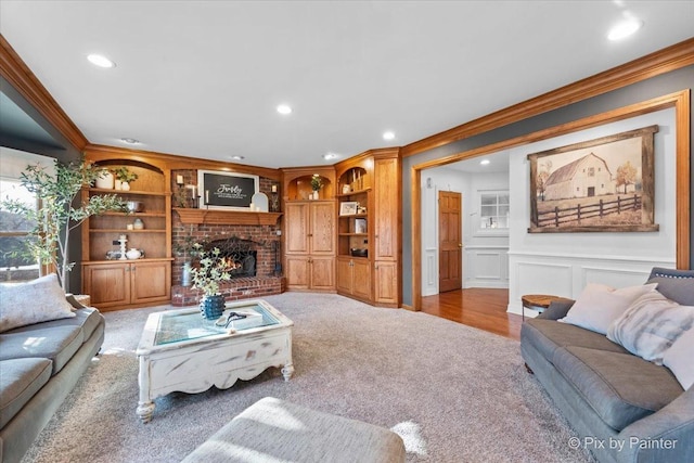 living area with a brick fireplace, ornamental molding, a decorative wall, and carpet flooring