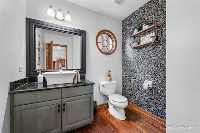 bathroom with toilet, baseboards, wood finished floors, and vanity