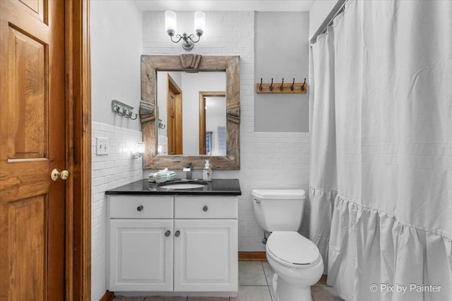 full bathroom featuring tile patterned flooring, toilet, a wainscoted wall, vanity, and tile walls