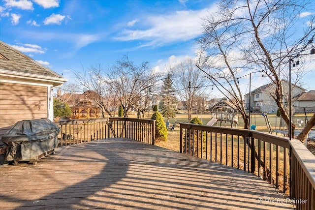 wooden terrace featuring a residential view, a playground, and area for grilling