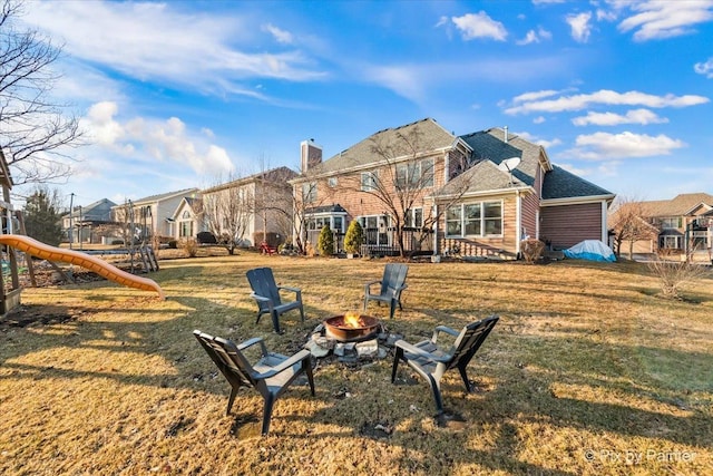 back of property with a residential view, a playground, a lawn, and a fire pit