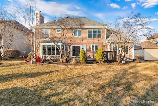 rear view of house with a chimney, a lawn, and a wooden deck