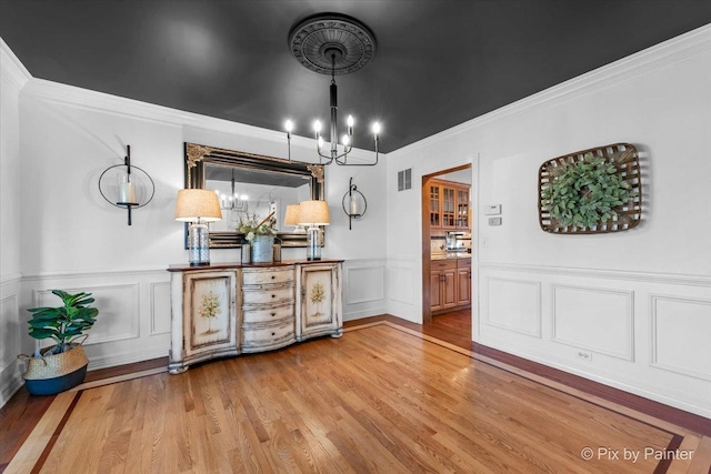 dining area with visible vents, ornamental molding, a notable chandelier, and wood finished floors