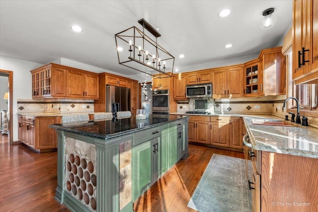 kitchen with a kitchen island, dark stone counters, stainless steel appliances, and dark wood finished floors