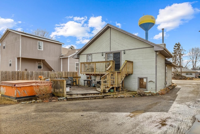 rear view of house featuring a hot tub, fence, and a deck