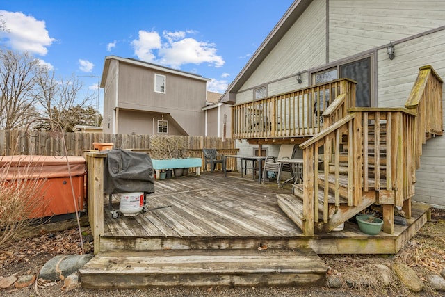 wooden deck featuring stairway, grilling area, fence, and a hot tub