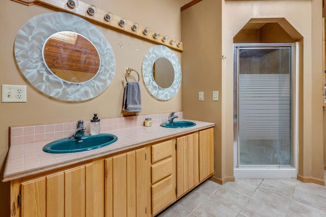 bathroom featuring a stall shower, double vanity, a sink, and tile patterned floors