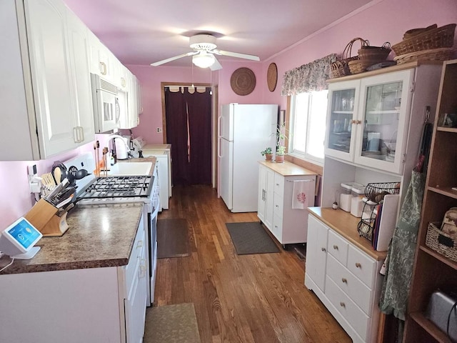 kitchen with white appliances, a sink, wood finished floors, white cabinetry, and glass insert cabinets