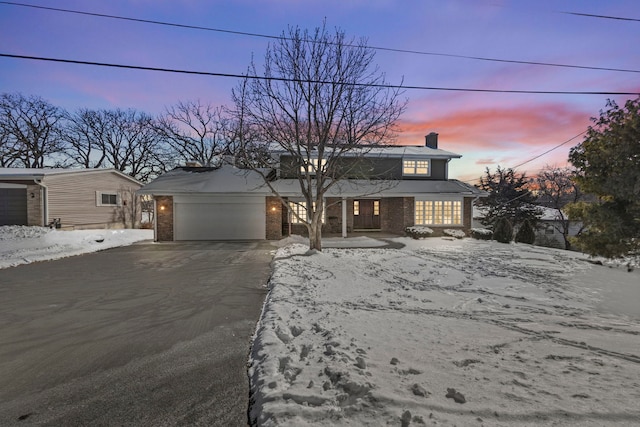 view of front of house featuring a garage, a chimney, aphalt driveway, and brick siding