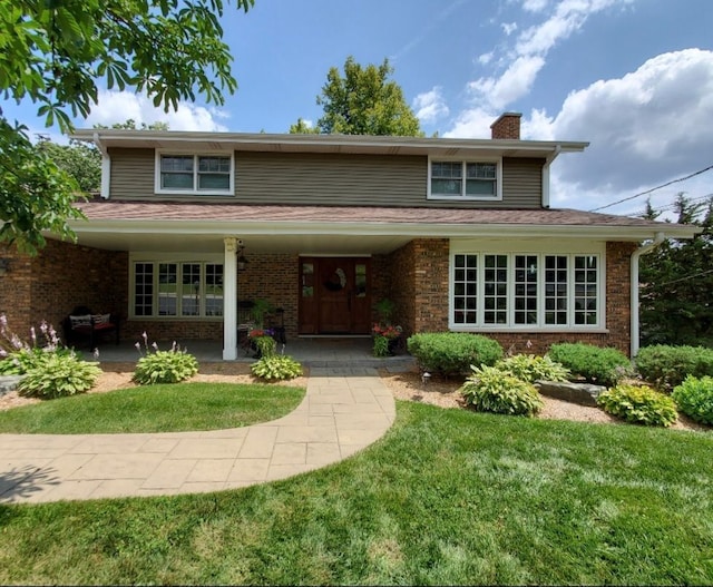 traditional-style house with brick siding, a chimney, and a front lawn