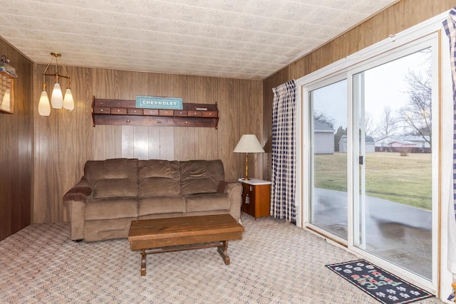 carpeted living area featuring a healthy amount of sunlight and wood walls